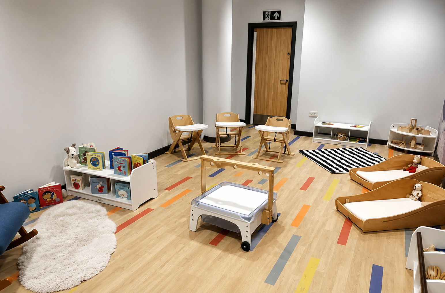 Baby room with sleeping cots, high chairs, a light table and a cosy book corner