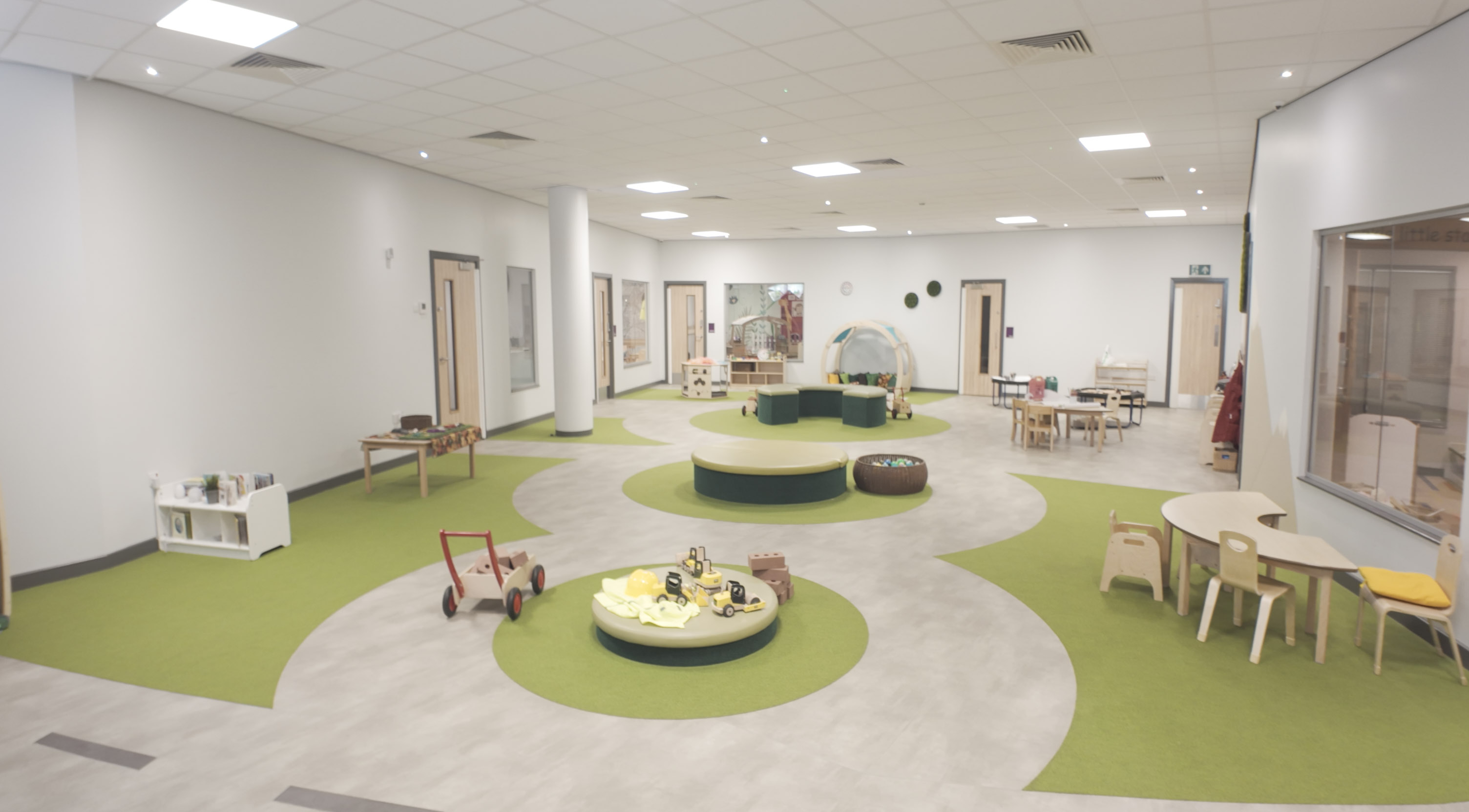 Large open playroom with ride-on toys and soft circular seating