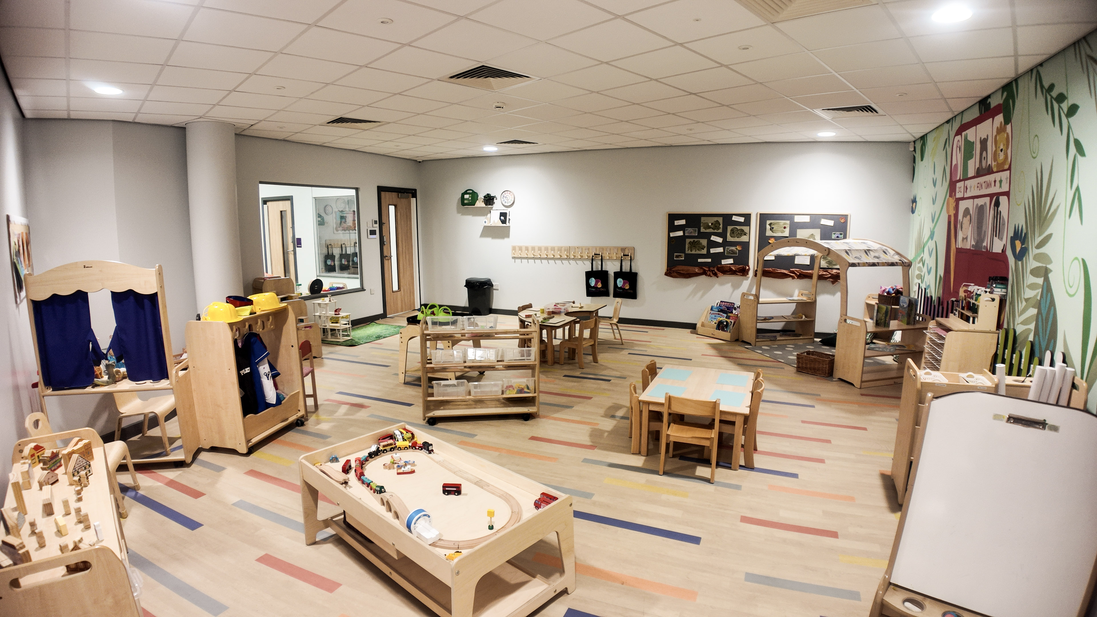 Preschool room with train table, puppet theatre and jungle mural